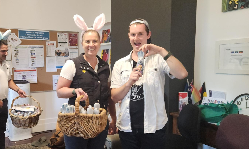Image description: Yooralla client holding an Easter chocolate egg. Bank staff member wearing bunny ears and holding a basket of chocolate eggs.