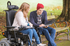 IMAGE: A person with disability and a support person are looking at a digital tablet and making plans together