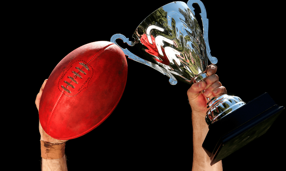 an image of one hand holding a football and a trophy in the other