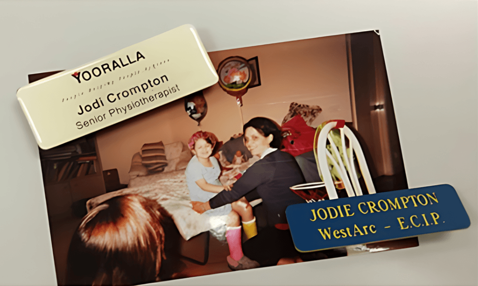 IMAGE: Jodi as a youth working with a physiotherapy client at a table - there are old Yooralla name badges sitting atop the photograph