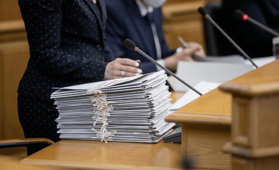 IMAGE: an Anonymous politician who is resting their hand on a pile of documents