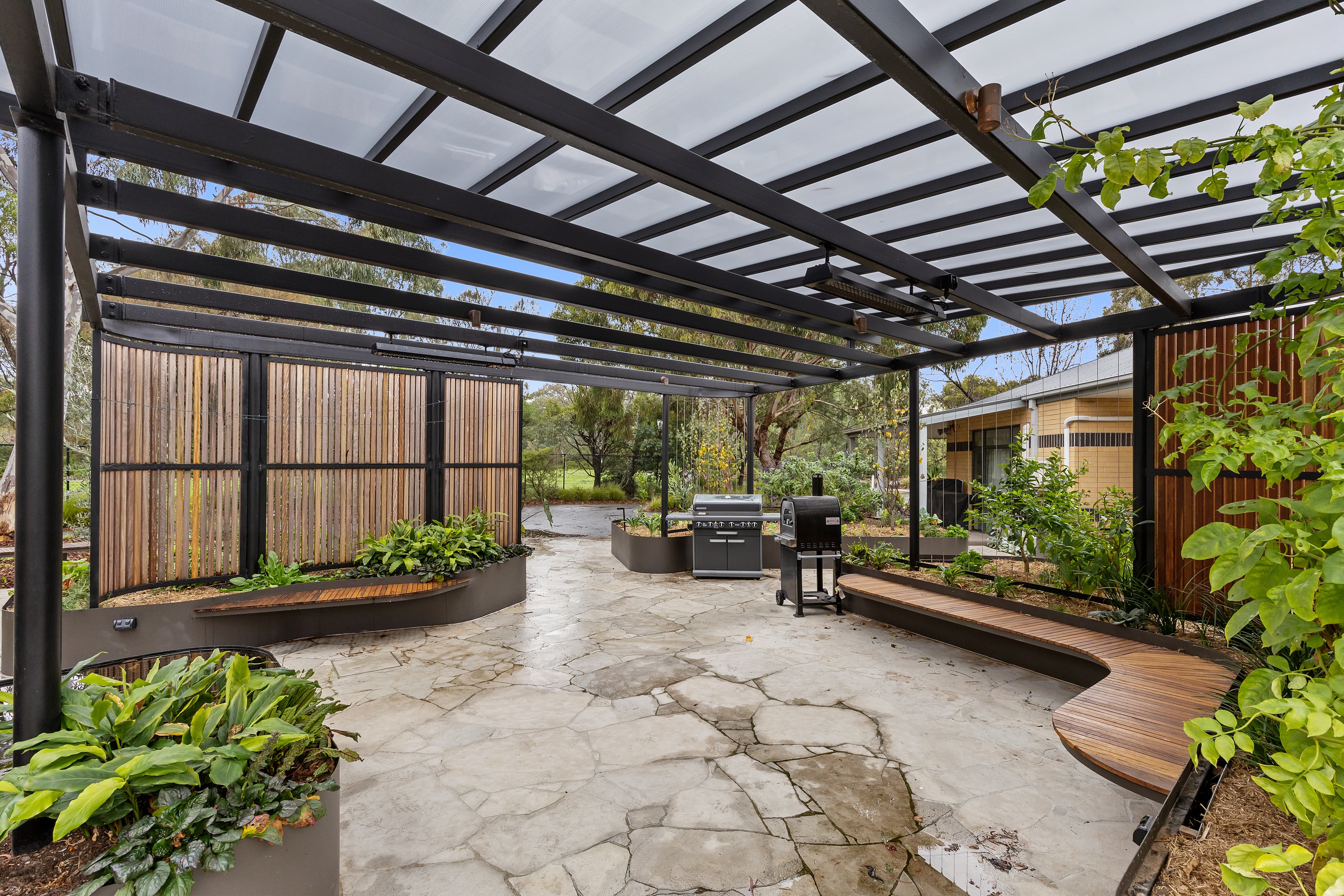 Image: Image of Thornbury Sensory Garden. Sheltered area with wooden benches and lots of green plants and herbs