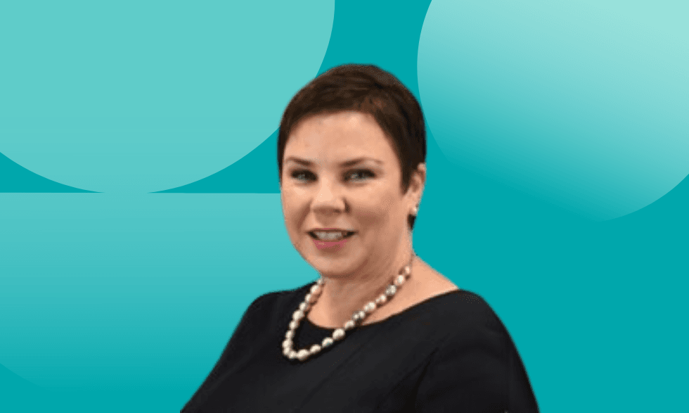 An image of Susie wearing black with colourful pearl jewellery smiling at camera