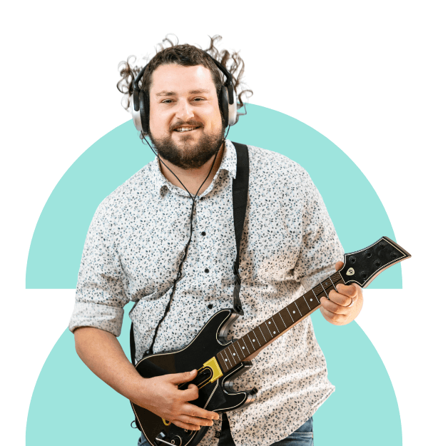 Yooralla client Matt is standing with a Guitar hero guitar in a rock pose- he is wearing headphones and having fun
